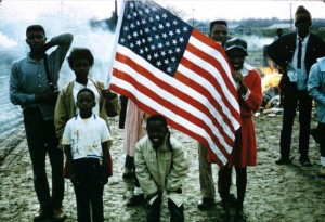 African American children with an American flag, probably during the Selma to Montgomery March. SSelma to Montgomery Rights March slide collection, Slide #2612, Alabama Dept. of Archives and History, Montgomery, Alabama.