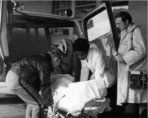 Reporter watching man loaded into ambulance. M004_2481, WSB Radio Records, Popular Music and Culture Collection, Special Collections and Archives, Georgia State University Library.